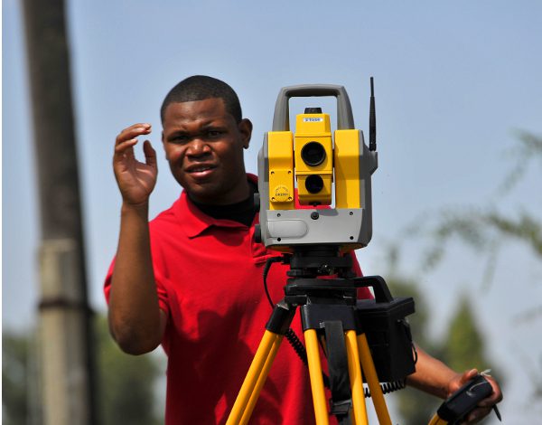 a black man performing a land survey looking focused