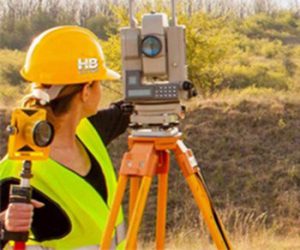A Woman Performing a Site Survey Close to Frederick Maryland. The scene is a hilly area with light scrub and deep green eastern pines on a beautiful sunny summer day.