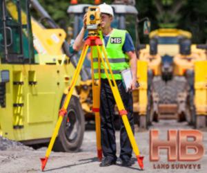 an image of a man standing in front of some heavy construction equipment performing a property survey on a bright sunny summer day