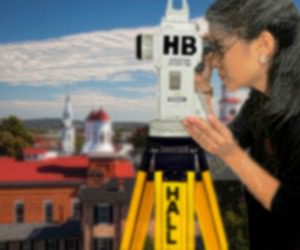 an image of a spanish woman looking through a theodolite with the skyline of the city of frederick maryland on a sunny Autumn day, it'svery colorful and beautiful